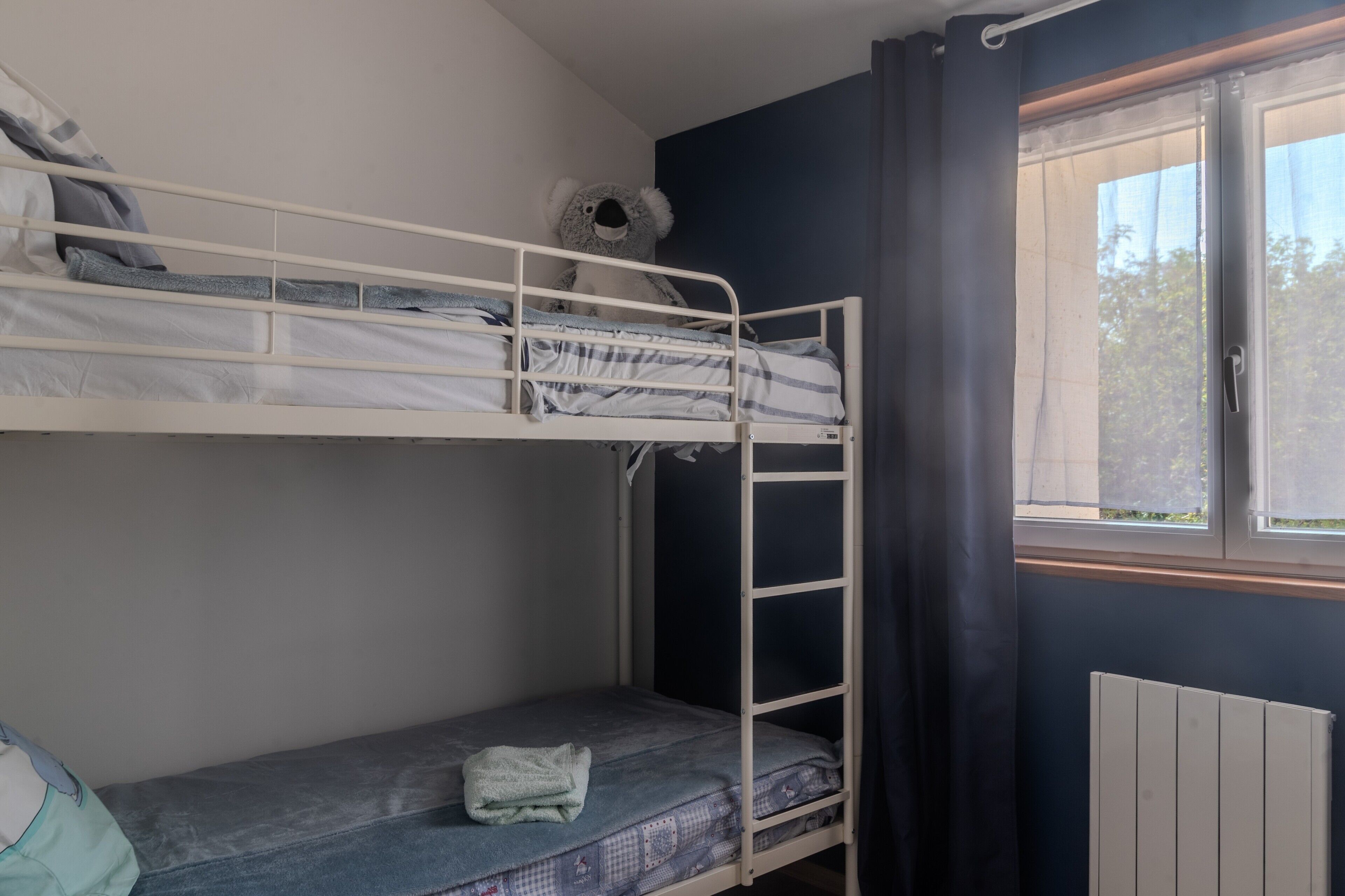 Habitación con literas, una ventana, un radiador y una toalla en la cama inferior.