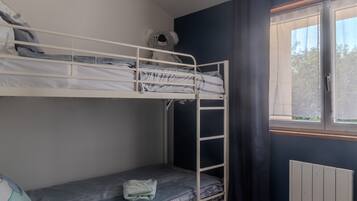 Habitación con literas, una ventana, un radiador y una toalla en la cama inferior.