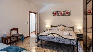 A bedroom with a bed, bedside tables, a chair, a wall art piece, and a door.