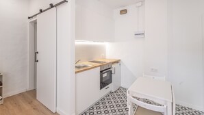 A compact kitchen with a wooden countertop, a built-in oven, and a white dining table. - Apartment 'Portblanc' with Balcony, Wi-Fi, and Air Conditioning (Arenys de Mar)