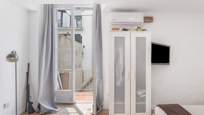 A bedroom with a bed, a wardrobe, a TV, and a balcony with a view. - Apartment 'Portblanc' with Balcony, Wi-Fi, and Air Conditioning (Arenys de Mar)