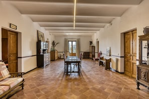 A spacious room with a wooden dining table, chairs, a sofa, and a cabinet.