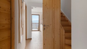 A wooden interior hallway with a staircase, a door, and a view of a balcony. - Apartment 'Prielerhof Sunrise' with Mountain View, Private Terrace and Wi-Fi (St. Lorenzen)