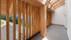 A wooden balcony with a view of a road and greenery. - Apartment 'Prielerhof Sunrise' with Mountain View, Private Terrace and Wi-Fi (St. Lorenzen)