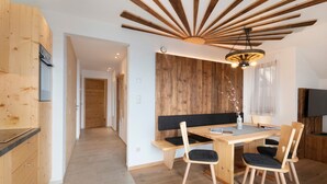 A modern kitchen with wooden cabinets, a dining area with a wooden table and chairs, and a ceiling with wooden beams. - Apartment 'Prielerhof Sunrise' with Mountain View, Private Terrace and Wi-Fi (St. Lorenzen)