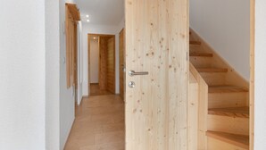 A wooden staircase leading to an upper floor, a wooden door with a handle, and a hallway with wooden flooring. - Apartment 'Sunset' with Mountain View, Private Terrace and Wi-Fi (St. Lorenzen)