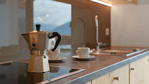 A kitchen with a coffee maker, cups, and a window with a view. - Apartment 'Sunset' with Mountain View, Private Terrace and Wi-Fi (St. Lorenzen)