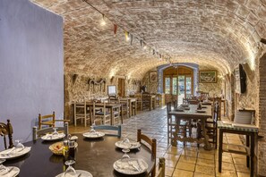 A rustic dining area with stone walls, wooden tables, and chairs. - Bed and Breakfast 'Estrella' with Shared Pool, Shared Terrace and Shared Garden (Serra de Daró)