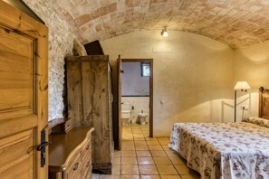 A rustic room with a wooden wardrobe, a bed with a floral bedspread, a tiled floor, and a brick ceiling. - Bed and Breakfast 'Estrella' with Shared Pool, Shared Terrace and Shared Garden (Serra de Daró)