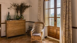 Una silla de mimbre, un aparador de madera y una ventana con cortinas.