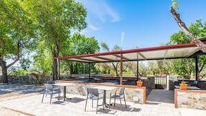 An outdoor patio with tables and chairs, a covered seating area, and a stone wall. - Mobile Home '243' with Mountain View, Wi-Fi and Air Conditioning (Tírig)