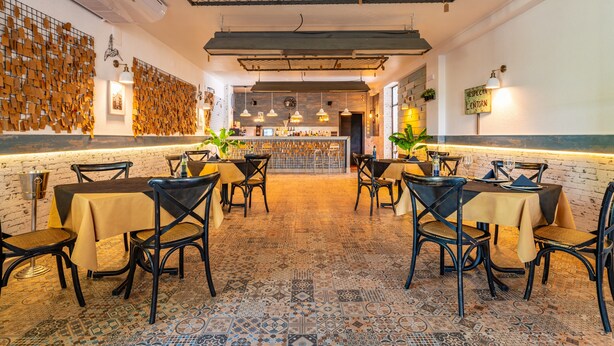 Un restaurante con zona de bar, suelo estampado e iluminación moderna.