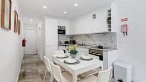 A modern kitchen with white cabinets, a marble backsplash, and a dining area with a white table set for two.