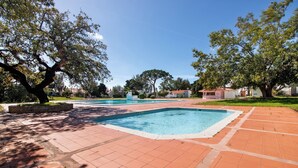 A swimming pool area with tiled flooring and trees.