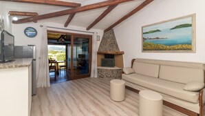 Una habitación con chimenea de piedra, un sofá, un televisor y vistas al exterior.