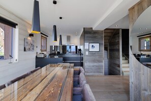 Een moderne keuken met een centraal eiland, hanglampen en uitzicht op de eethoek.