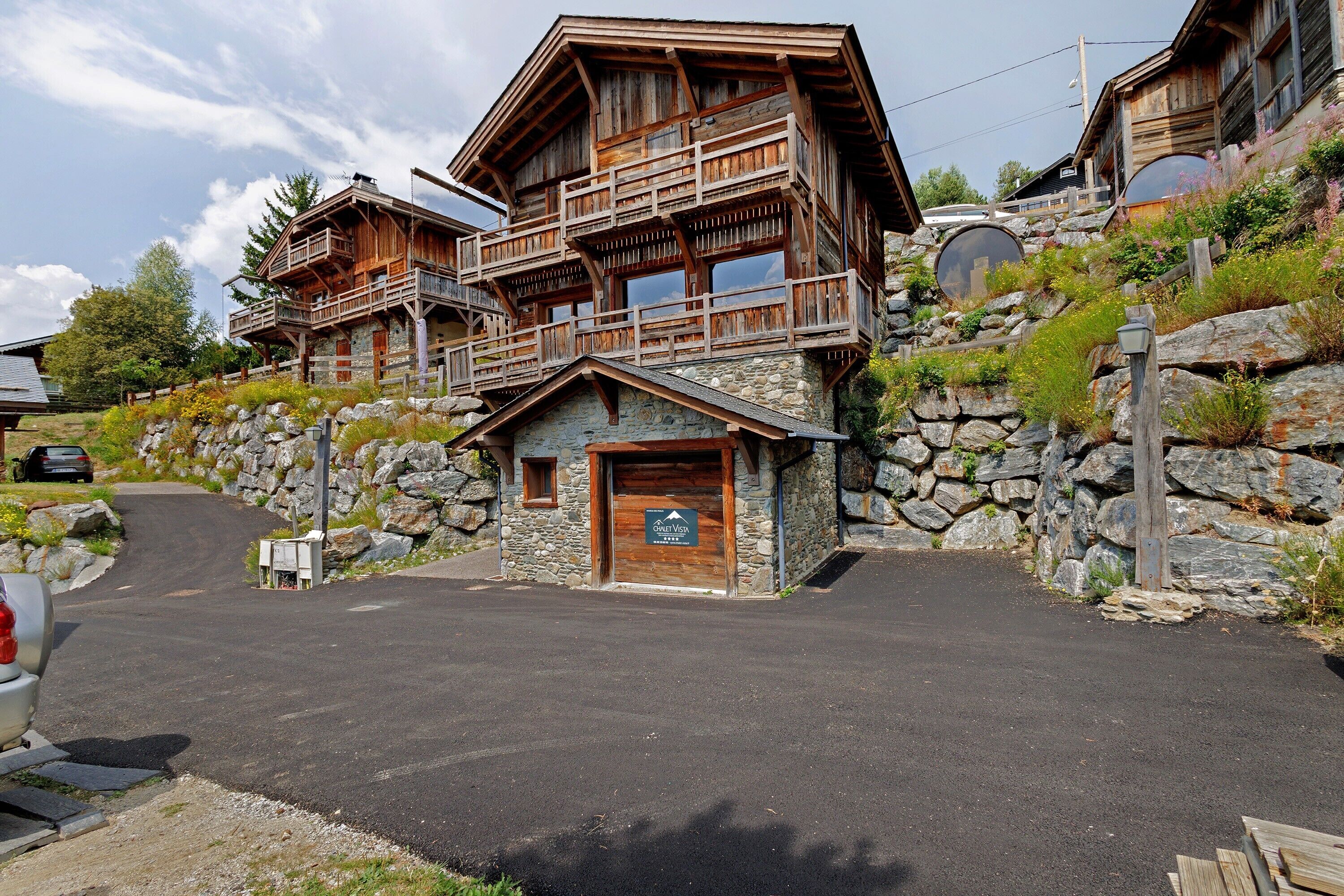 A multi-story log cabin with a stone foundation, wooden balconies, and a sign indicating a ski resort.