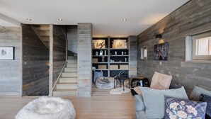 Un intérieur moderne avec un escalier, des murs en bois, un canapé et une bibliothèque.