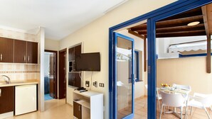 A modern kitchen with a built-in fridge, a dining area with a table and chairs, and a TV mounted on the wall.