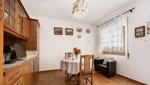 A dining area with a table, chairs, a sofa, and a kitchen area with cabinets and a countertop. - Holiday Home 'Acolhedora' with Private Garden, Wi-Fi and Air Conditioning (Lagos)