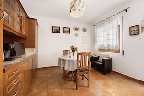 Un comedor con mesa, sillas, sofá y una zona de cocina con armarios y encimera.