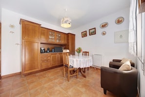 A kitchen with wooden cabinets, a dining table with chairs, and a sofa.