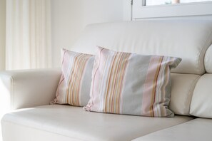 A white leather sofa with two striped pillows. - Apartment 'Ses Roques' with Sea View, Wi-Fi and Air Conditioning (Son Servera)