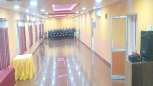 A spacious hall with rows of chairs, a stage with a yellow table, and a sound system on the right. - Hotel St Thomas International Centre (Chennai)