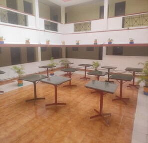 A multi-level indoor space with tiled floors and multiple tables and chairs. - Hotel St Thomas International Centre (Chennai)