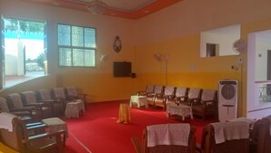 A church interior with rows of pews, a red carpet, a chandelier, and a large window. - Hotel St Thomas International Centre (Chennai)