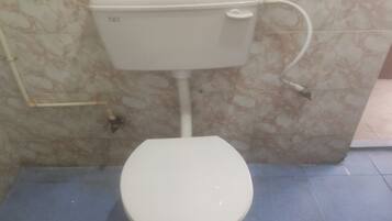 En toalett med en vit cistern och sits, placerad framför en vägg med marmorliknande mönster, och med ett blått golv.
