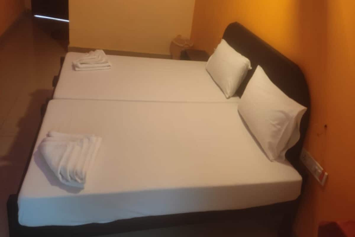 Un llit doble amb roba de llit blanca, dos almoines i una tovallola doblegada al costat esquerre.