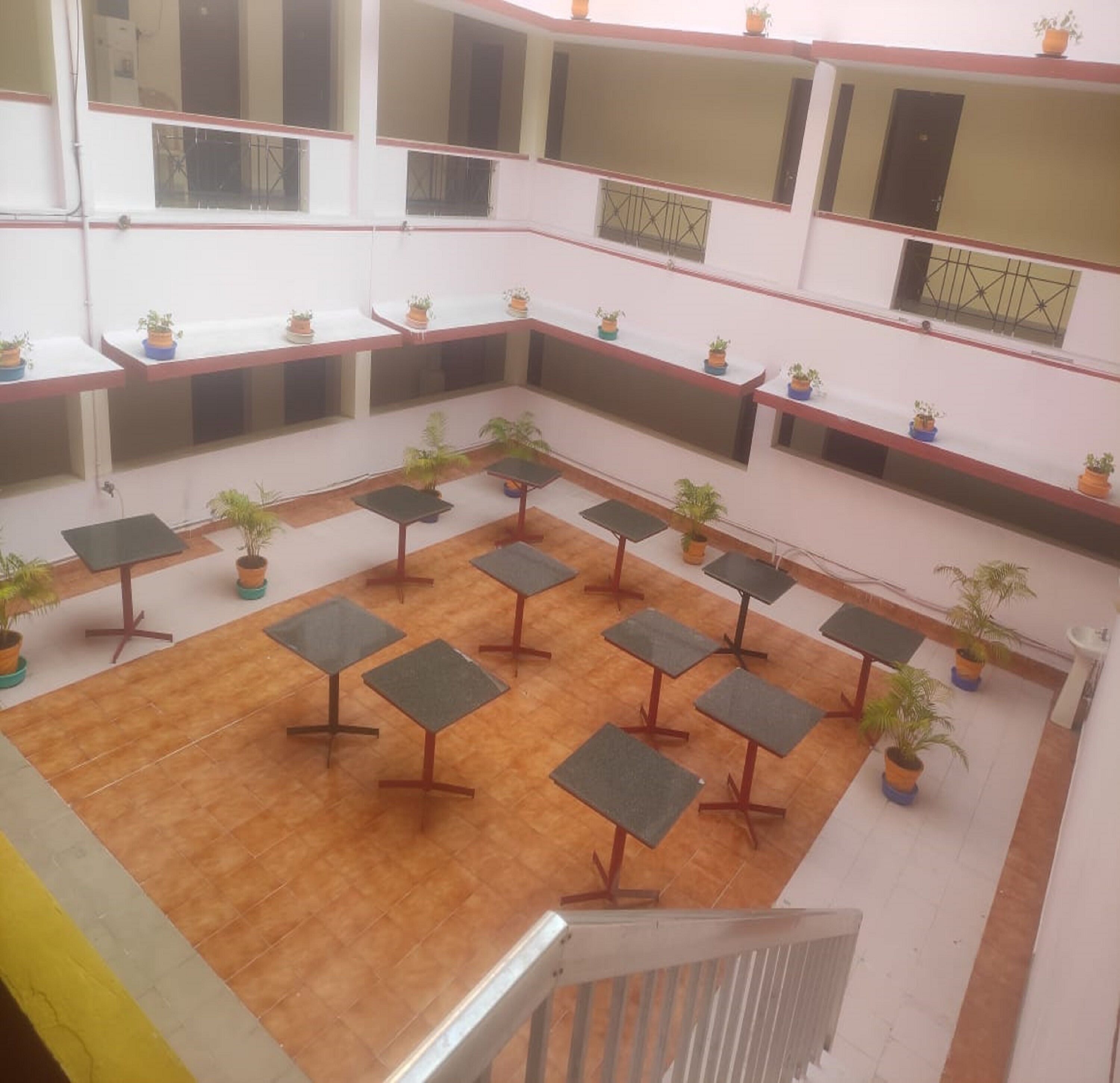 A multi-level atrium with a wooden floor, multiple tables, and potted plants.