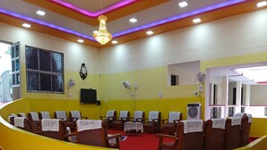 A room with yellow walls, a red carpet, and a curved seating area with chairs. - Hotel St Thomas International Centre (Chennai)