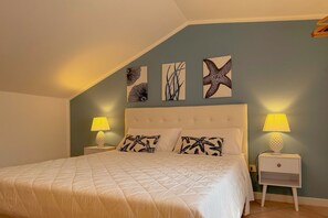Ein Schlafzimmer mit einem großen Bett, zwei Nachttischen mit Lampen und drei Wandbildern.
