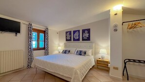 A bedroom with a bed, a TV, a window with curtains, and wall art.