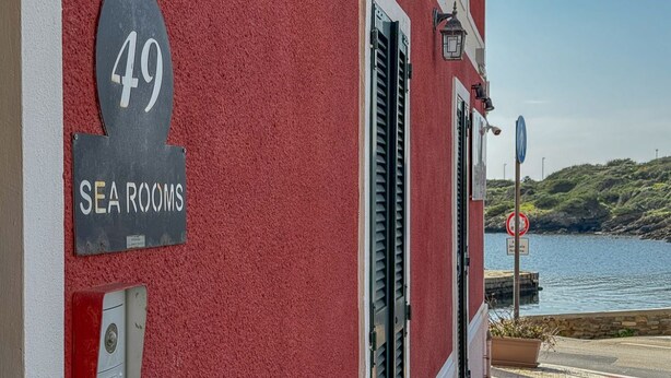 A building with a sign indicating 'SEA ROOMS' and the number '49' on a red wall.