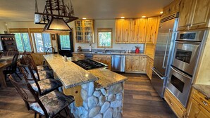 A spacious kitchen with a large island, wooden cabinets, and stainless steel appliances. - PICKLEBALL Paradise! HotTub/Huge GameRoom/Mtn views/Fido Friendly/best location! (Grand Lake)