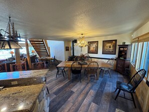 Un vaste espace dédié à la salle à manger, avec une table et des chaises en bois, un lustre et des œuvres d’art encadrées qui ornent les murs.