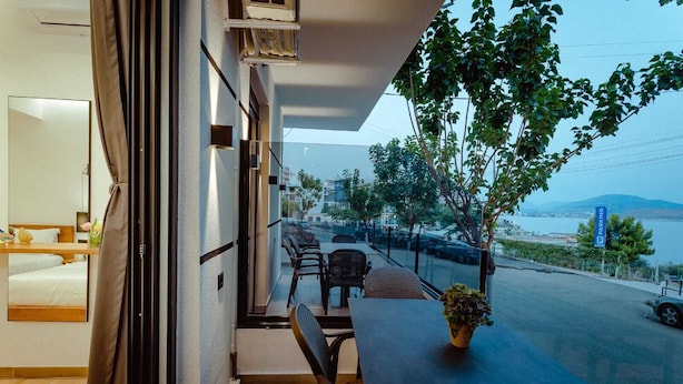 A balcony with a table and chairs, a view of the sea, and a parking sign. - Gloal Suites Residence (Sarande)