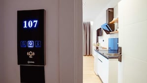A digital keypad with the number 107 and icons for room service, check-in, and a bell. - Gloal Suites Residence (Sarande)
