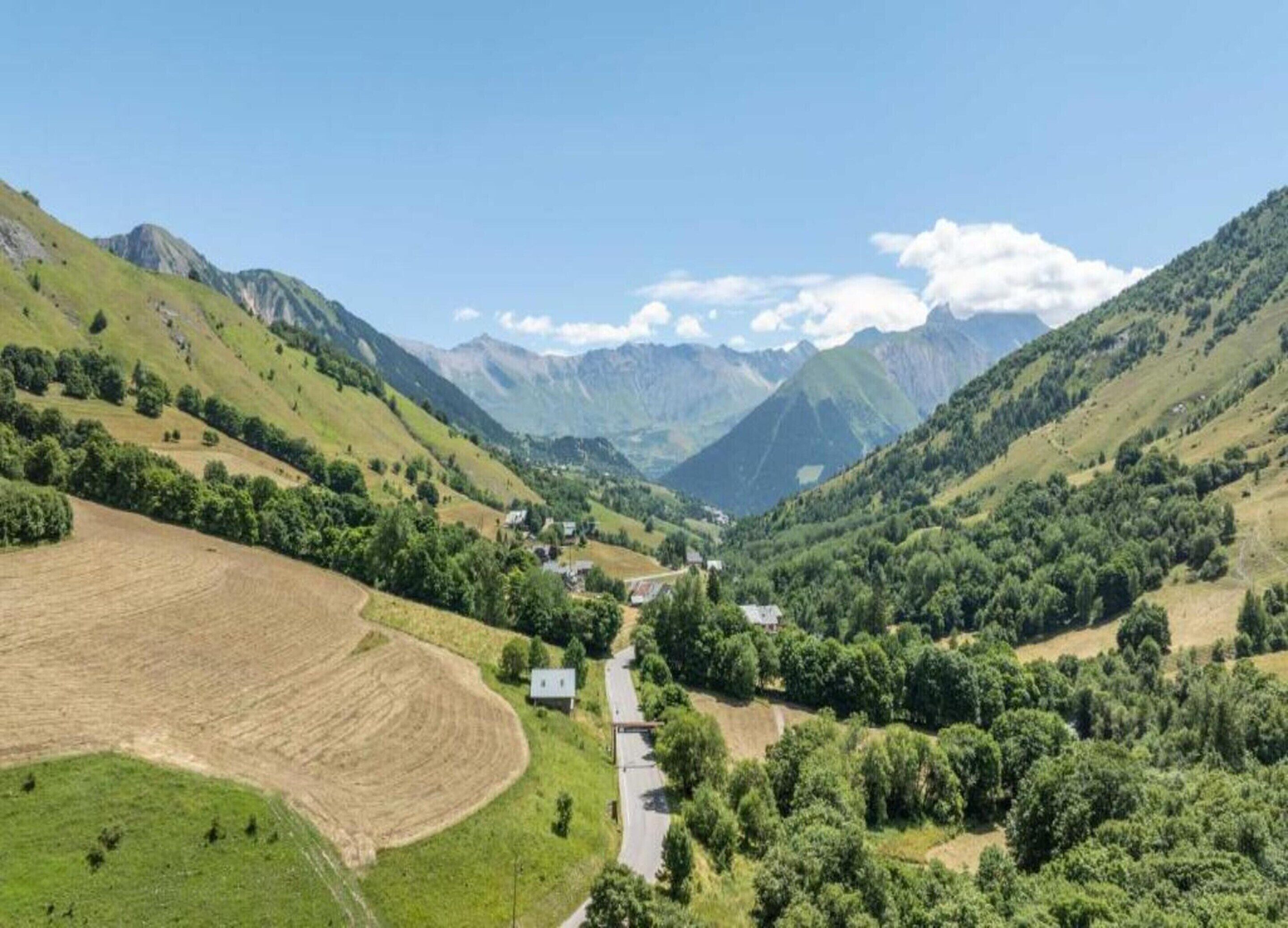 A valley with a road, houses, and green fields.