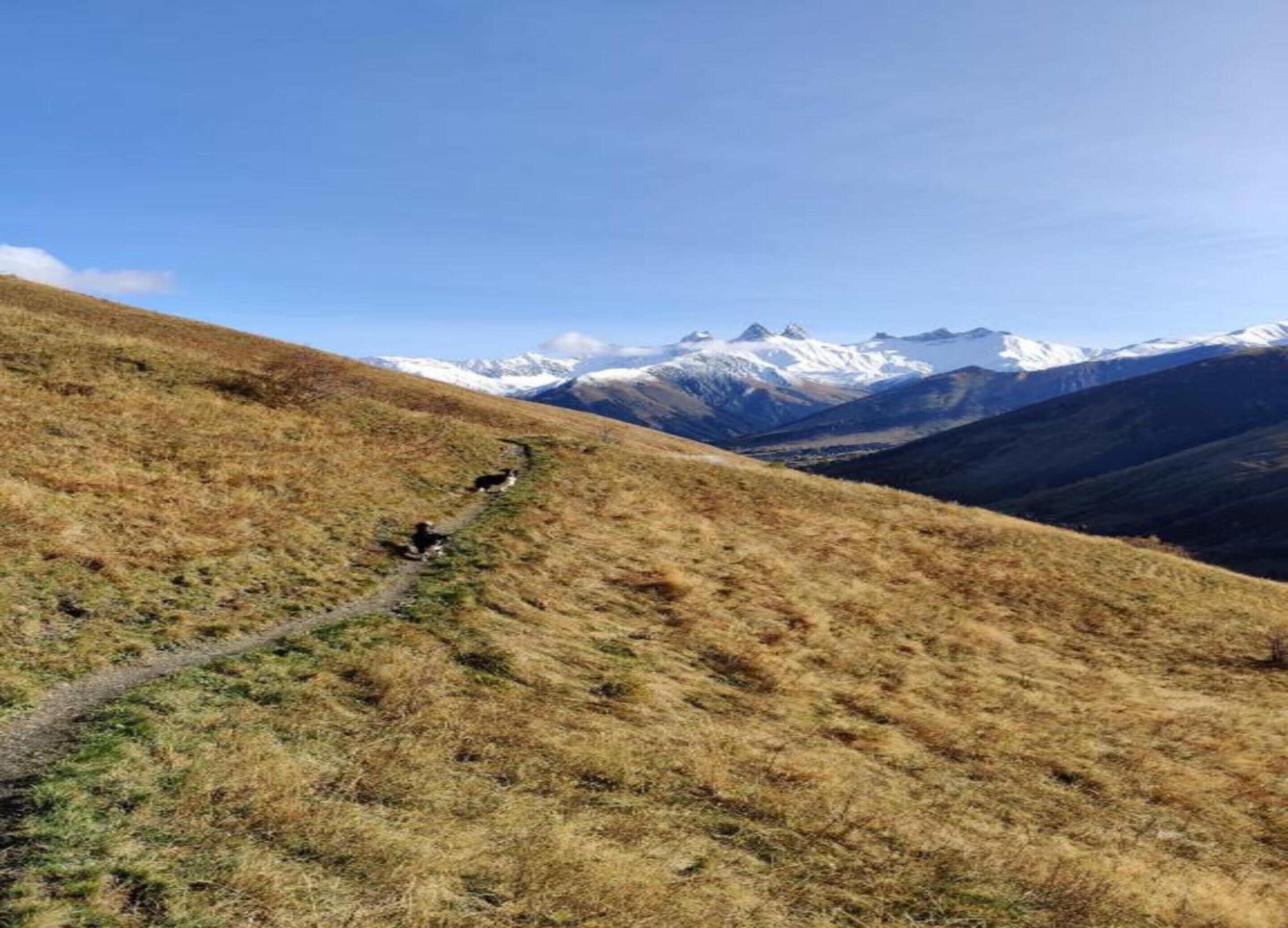 A mountainous landscape with a clear sky and a path leading to a peak.