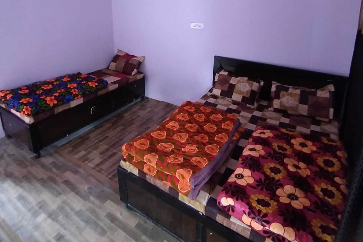 A bedroom with two beds, a small table, and a wardrobe.