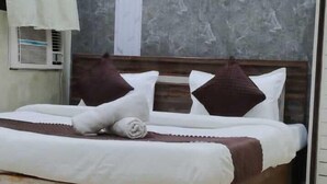 A neatly made bed with a wooden headboard, a marble wall, and a ceiling with a circular design. - Hotel Mahaveer International (Varanasi)