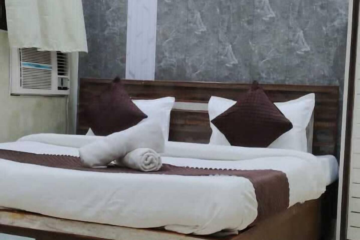 Una cama bien hecha con cabecera de madera, pared de mármol y techo con diseño circular.