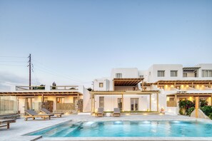 A modern villa with a swimming pool, outdoor seating, and a covered patio. - Athera  Suites  Mykonos (Mykonos)