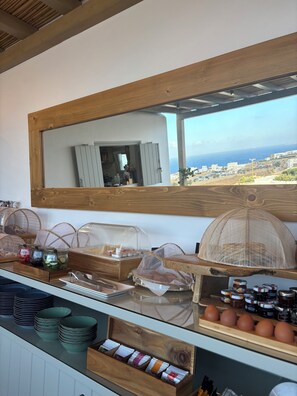 A breakfast bar with a wooden counter, a mirror, and a view of the sea. - Athera  Suites  Mykonos (Mykonos)