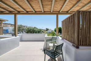 A covered outdoor seating area with a view of the landscape. - Athera  Suites  Mykonos (Mykonos)