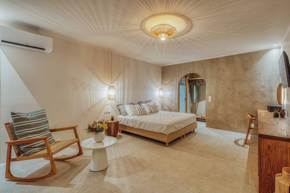 A modern bedroom with a bed, a chair, a small table, and a TV.